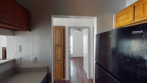 a kitchen with a refrigerator and a door to a hallway