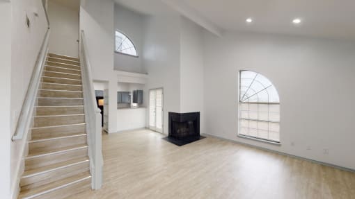 a living room with a staircase and a fireplace and white walls and floors