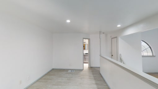 a living room with white walls and a window and a staircase