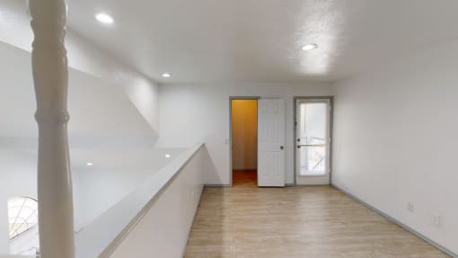 a renovated living room with white walls and white stairs and a white door
