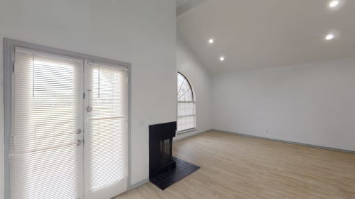 a living room with white walls and a door with blinds on it