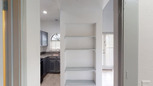 the closet in a small apartment with open shelving and a kitchen