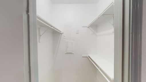 a white room with a window and a white shelf in it
