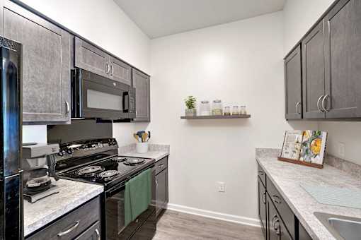 A kitchen with a black stove top oven and a black microwave.