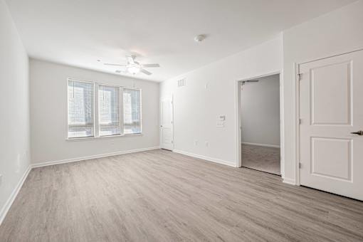 A room with a ceiling fan and a door leading to another room.