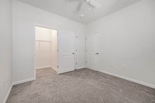 A room with a carpeted floor and a ceiling fan.