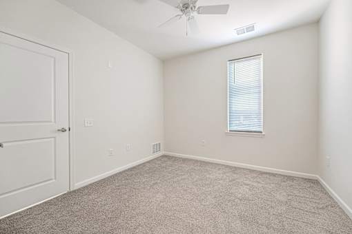 A room with a ceiling fan and a window with blinds.