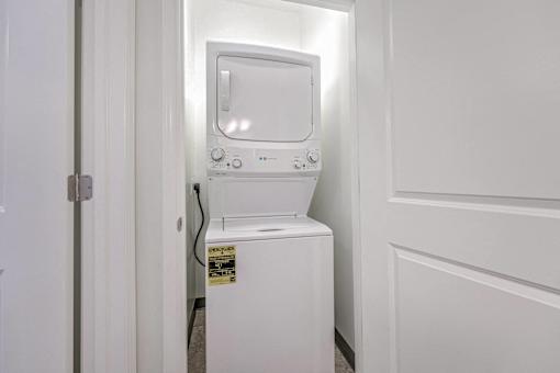 A white washing machine is in a small white room.