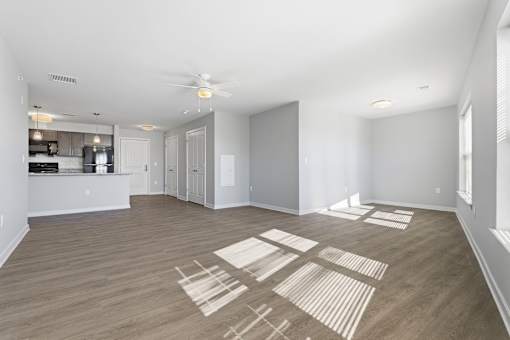 A spacious room with a ceiling fan and wooden flooring.