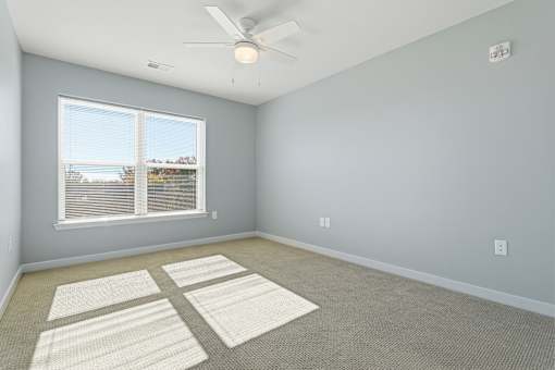 A room with a ceiling fan and a window with blinds.