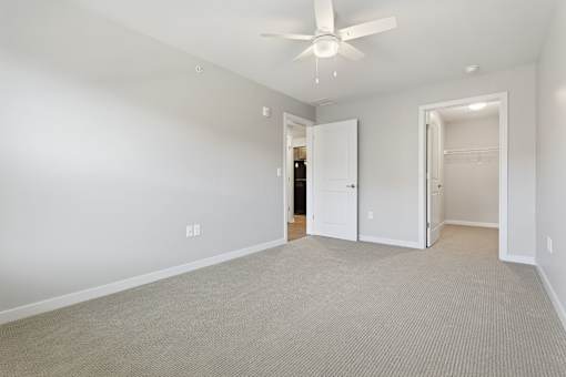 A room with a ceiling fan and carpeted floor.