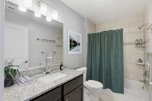 A bathroom with a white toilet, a sink, and a green shower curtain.