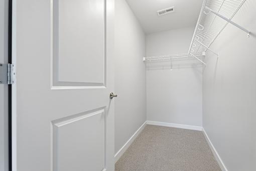 A white door is on the left of a hallway with a carpeted floor.