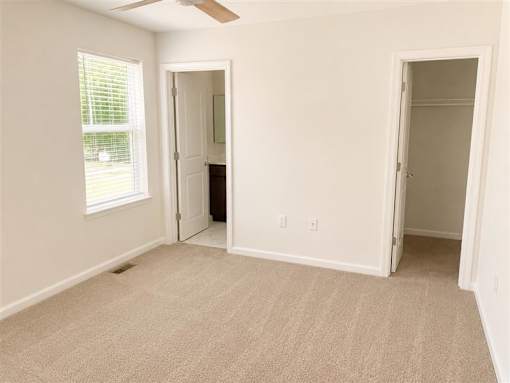 A room with a carpeted floor and a window with blinds.