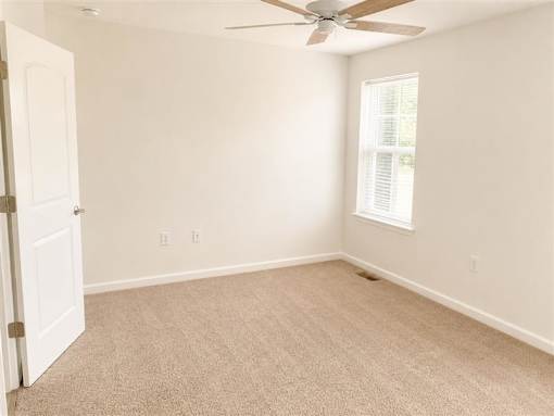 A room with a ceiling fan and a window with blinds.