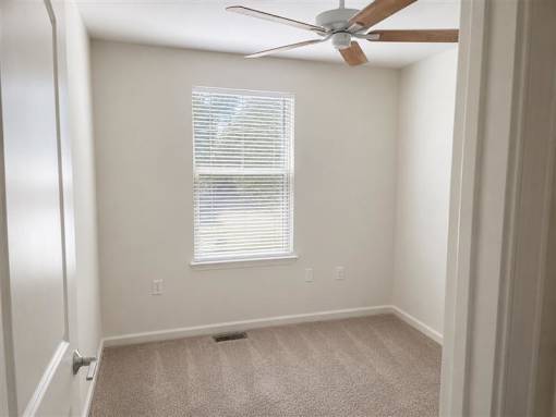 A room with a ceiling fan and a window with blinds.