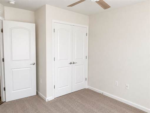 A room with two white doors and a ceiling fan.