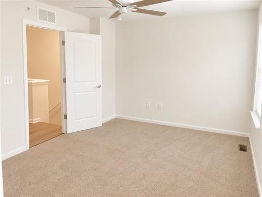 A room with a ceiling fan and carpeted floor.
