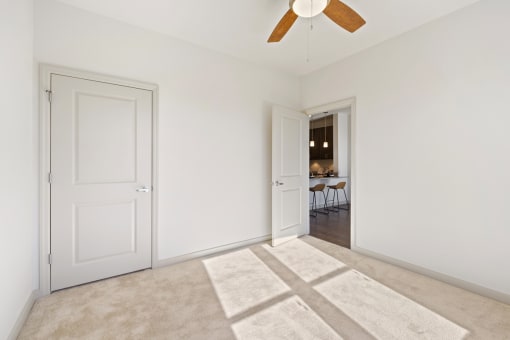 a bedroom with white walls and a ceiling fan