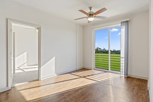 a living room with a ceiling fan and a door that leads to a balcony