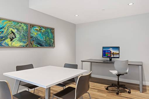 A white table with chairs and a computer on a desk in a room.