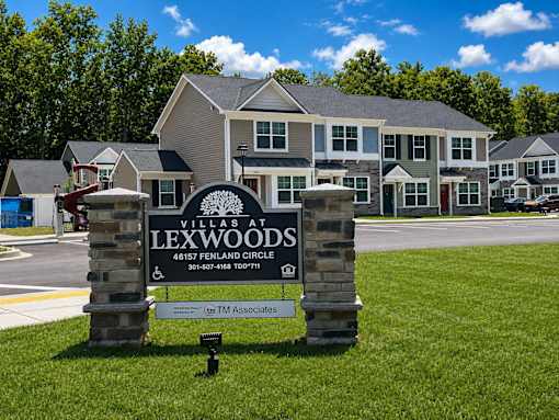 A sign for Lexwood Villas is in the foreground with houses in the background.