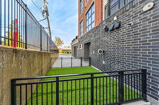 A black metal fence surrounds a green lawn.