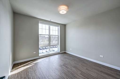 A room with a large window and wooden flooring.