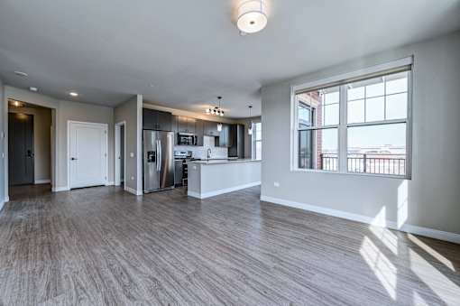 A spacious kitchen with wood flooring and a large window.