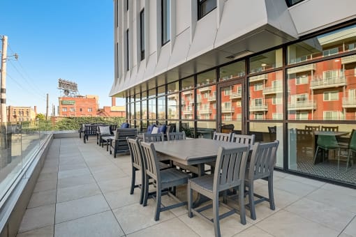 a patio with tables and chairs on the side of a building