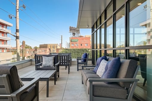 a balcony with couches and chairs and a baseball field in the background