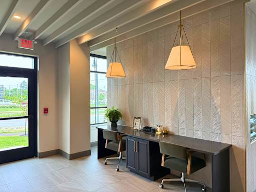 A modern office space with a desk, chairs, and a hanging light fixture.