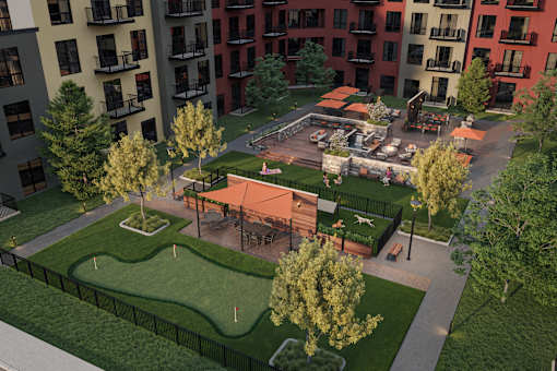 A park area with a playground and a green lawn surrounded by apartment buildings.
