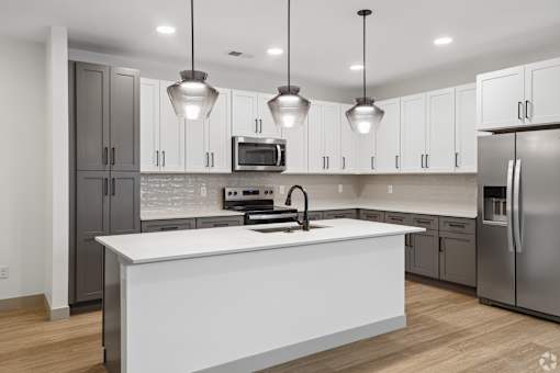 A modern kitchen with a white island and stainless steel appliances.