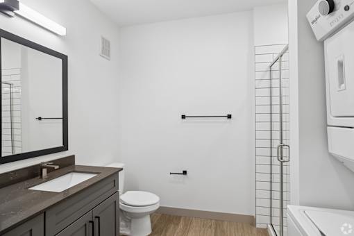 A white bathroom with a toilet, sink, and a shower.