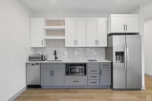 A kitchen with a refrigerator, microwave, and sink.