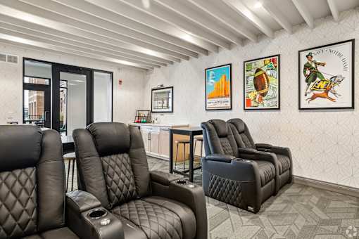 A row of black leather recliner chairs are lined up in a waiting room.