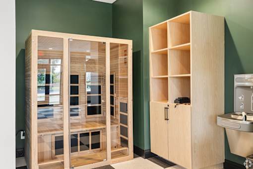 A wooden cabinet with glass doors and shelves is next to a sink in a room.
