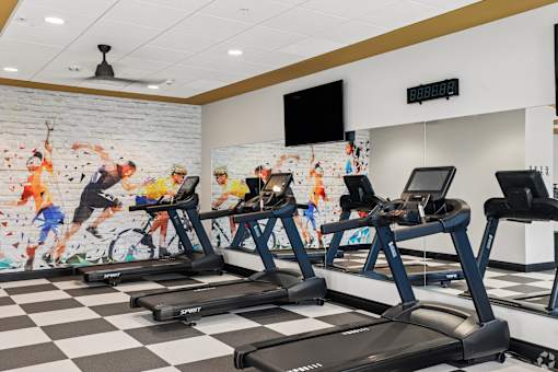 A gym with treadmills and a wall mural.