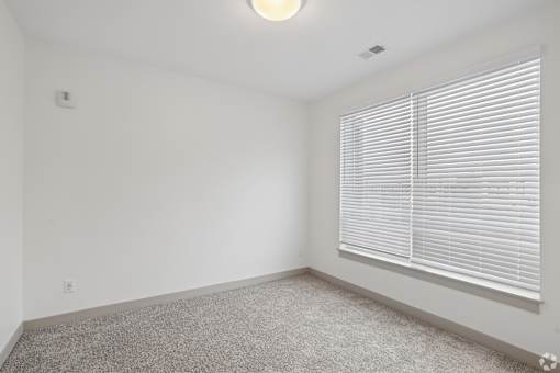 A room with a window covered by white blinds.