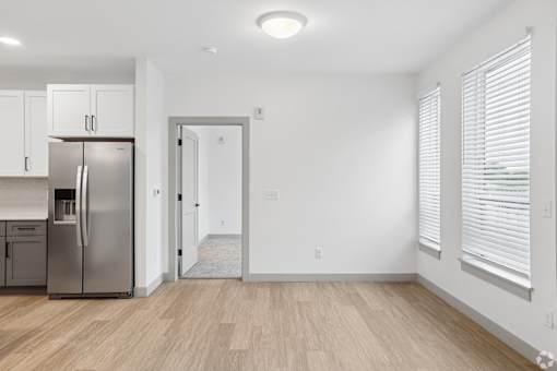A kitchen with a refrigerator, cabinets, and a doorway leading to another room.