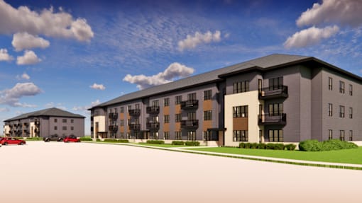 A modern apartment complex with a parking lot in front.