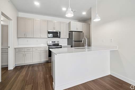 A modern kitchen with wooden floors and white appliances.