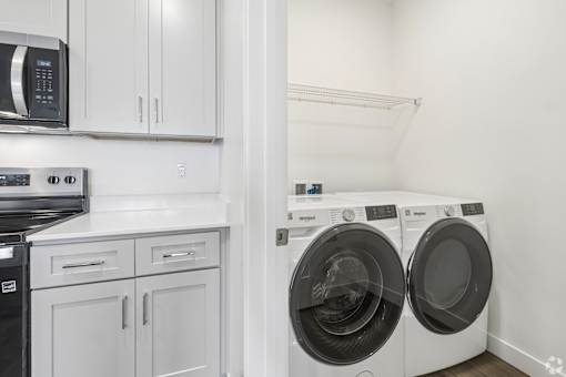 A white kitchen with a black fridge, microwave, and dishwasher.
