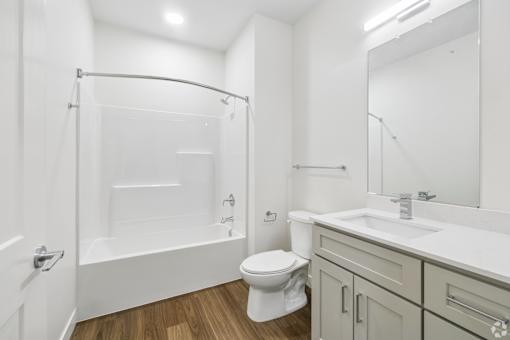 A white bathroom with a toilet, sink, and shower.