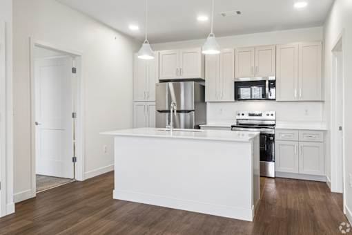 A white kitchen with wooden floors and white cabinets.