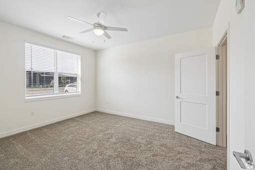 A room with a ceiling fan and a window with blinds.