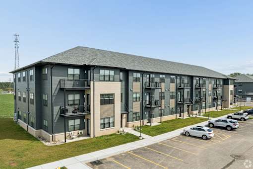 A large grey building with a parking lot in front.