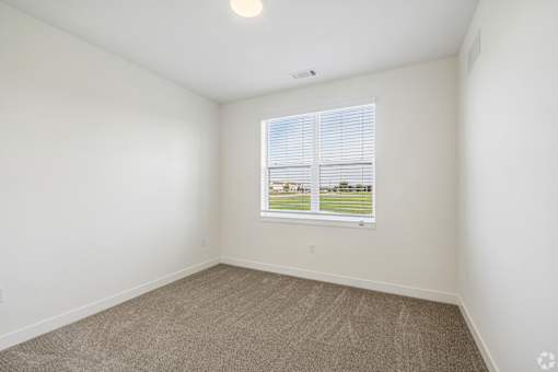 A room with a window showing a view of a grassy area.