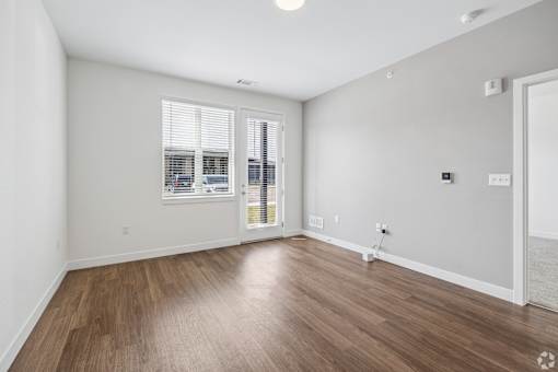 A room with wooden flooring and a window with blinds.